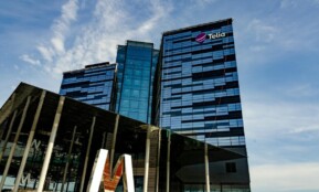 Modern glass office building in Stockholm with Telia logo on a sunny day.