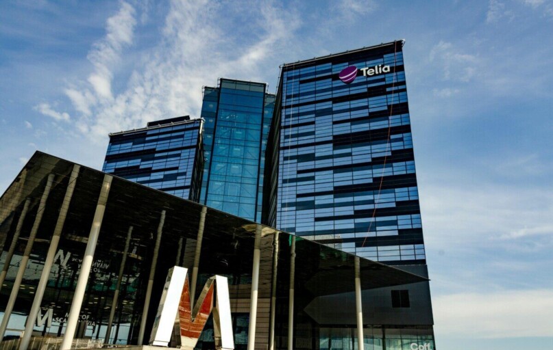 Modern glass office building in Stockholm with Telia logo on a sunny day.