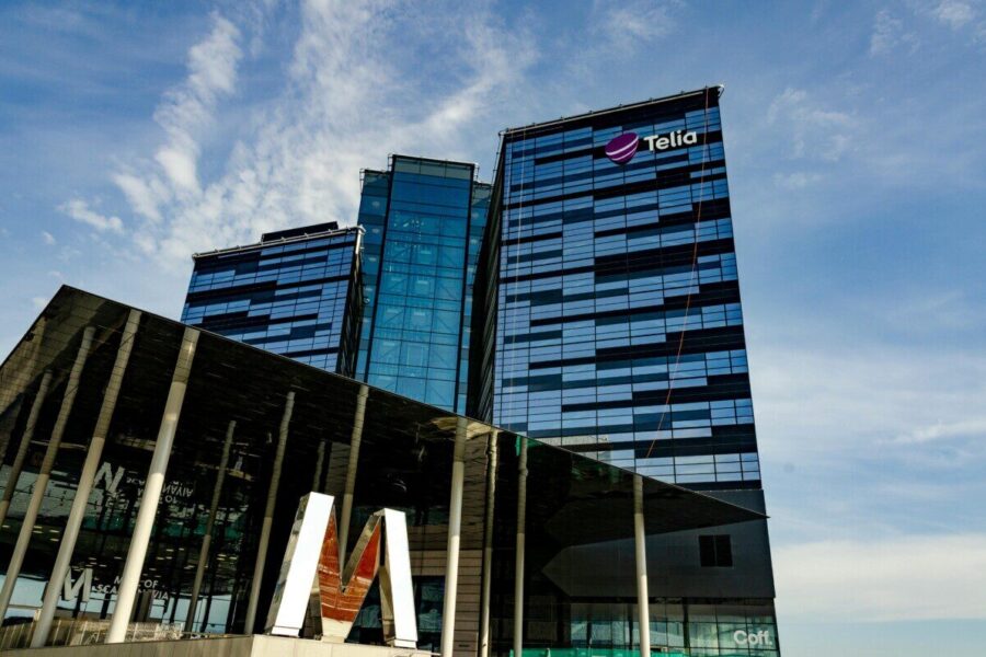 Modern glass office building in Stockholm with Telia logo on a sunny day.