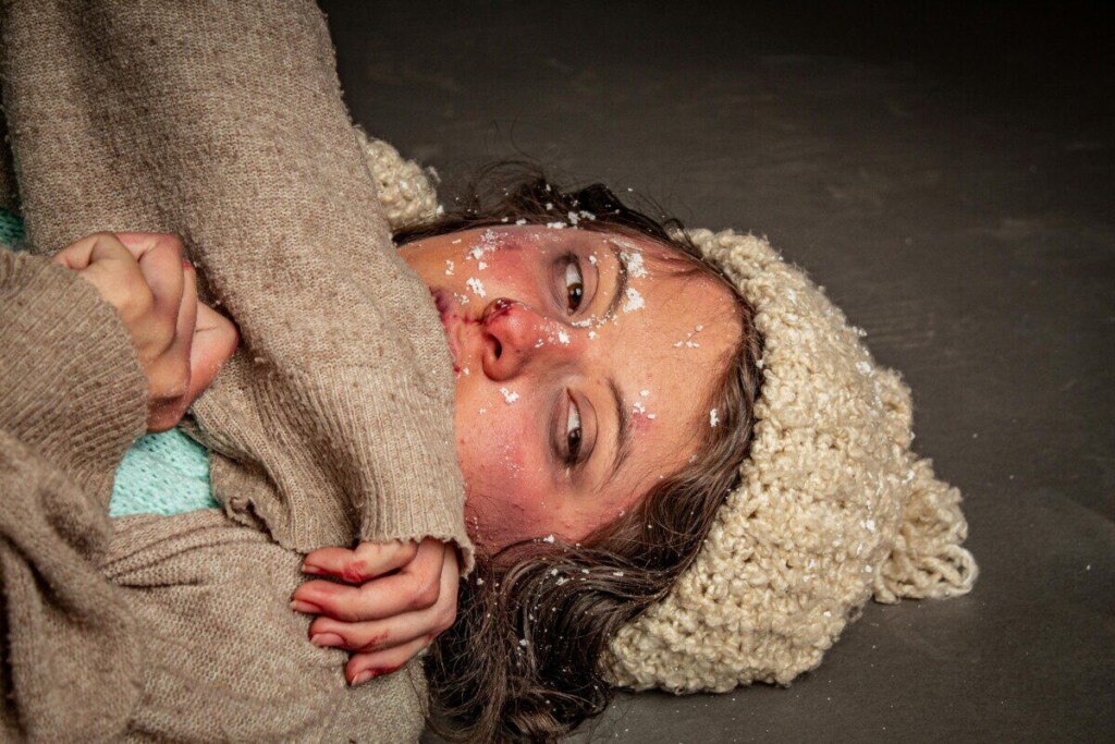 A woman portrayed as cold and distressed in a winter survival setting.