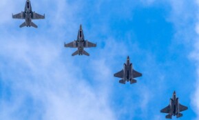 A formation of five military jets flying high against a blue sky in Albacete, Spain.