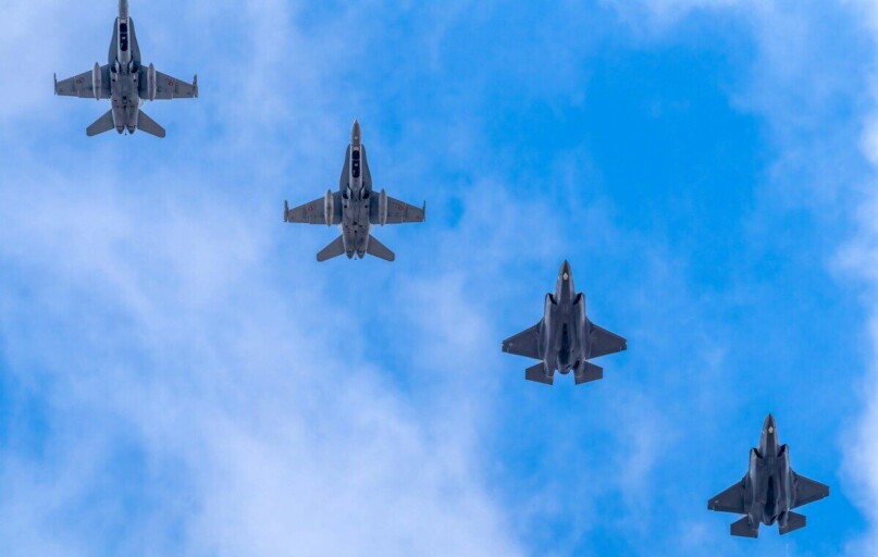 A formation of five military jets flying high against a blue sky in Albacete, Spain.