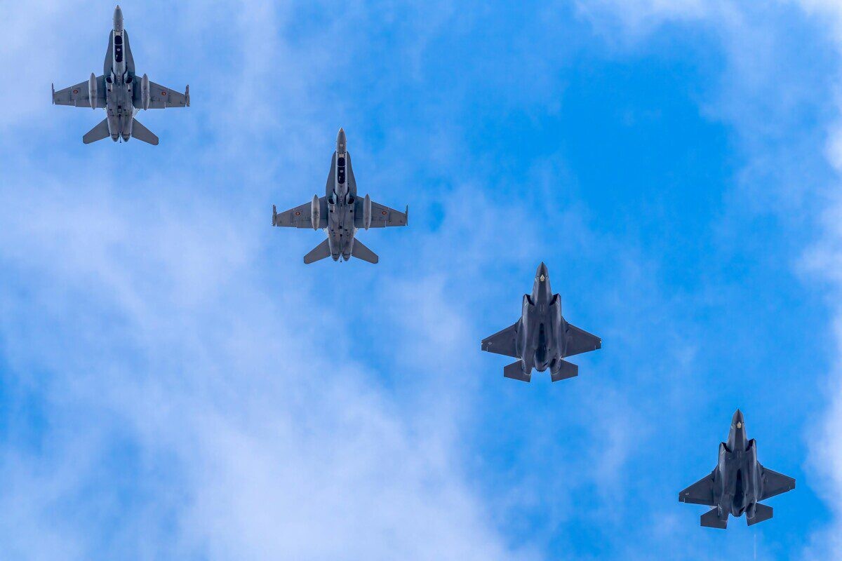 A formation of five military jets flying high against a blue sky in Albacete, Spain.