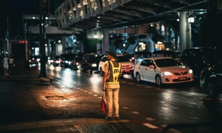 Traffic officer directs busy street traffic at night in Bangkok, Thailand.