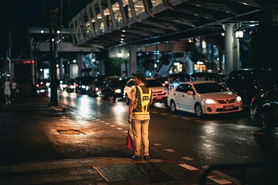 Traffic officer directs busy street traffic at night in Bangkok, Thailand.