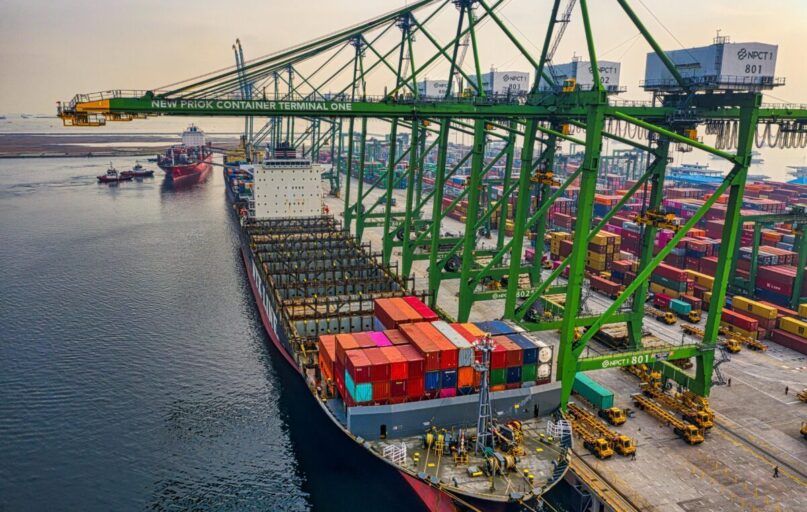 Aerial view of a cargo ship docked at New Priok Container Terminal, Jakarta, showcasing vibrant logistics activity.