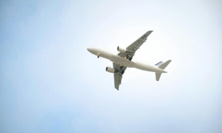 A white commercial airplane flying high against a clear blue sky, showcasing aviation dynamics.