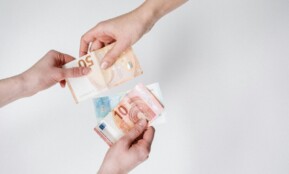 Close-up of hands exchanging euro bills, symbolizing finance and transaction.