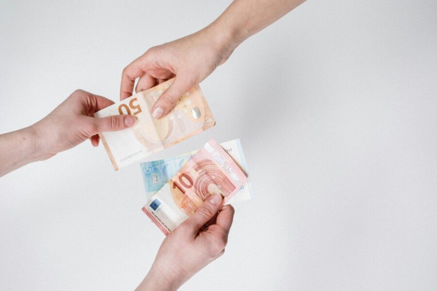 Close-up of hands exchanging euro bills, symbolizing finance and transaction.