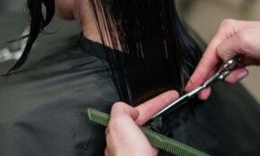 Close-up of a hairstylist cutting a woman's hair in a salon, showcasing precise techniques.