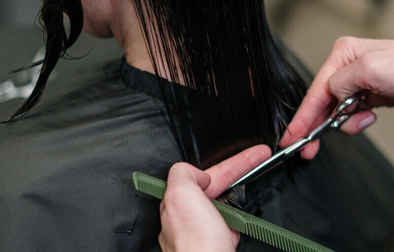 Close-up of a hairstylist cutting a woman's hair in a salon, showcasing precise techniques.
