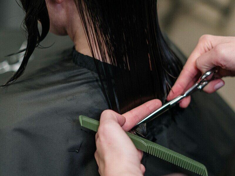 Close-up of a hairstylist cutting a woman's hair in a salon, showcasing precise techniques.