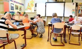 Children engaged in learning with a teacher in a bright classroom setting.