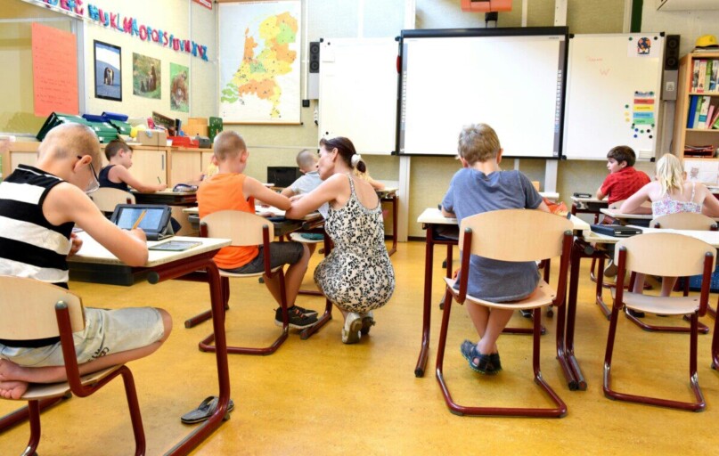 Children engaged in learning with a teacher in a bright classroom setting.