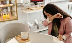 Woman covering a sneeze in a modern cafe, capturing everyday health concerns.
