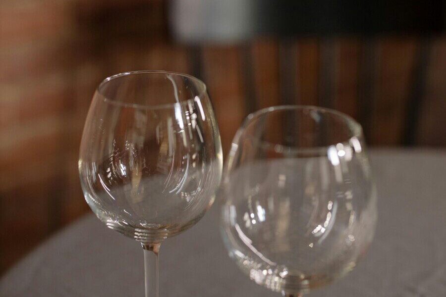 Two wine glasses on a table with a brick wall background create a cozy ambiance.
