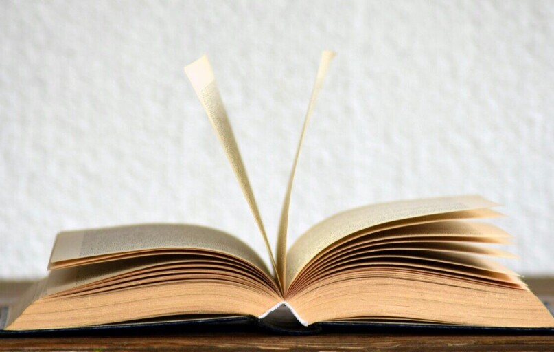 Close-up image of an open book with pages turning, creating a dynamic visual.