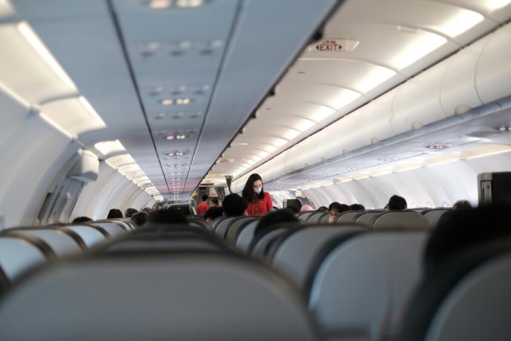 Passengers and flight attendant inside a Vietnam commercial aircraft. Travel safety with masks.