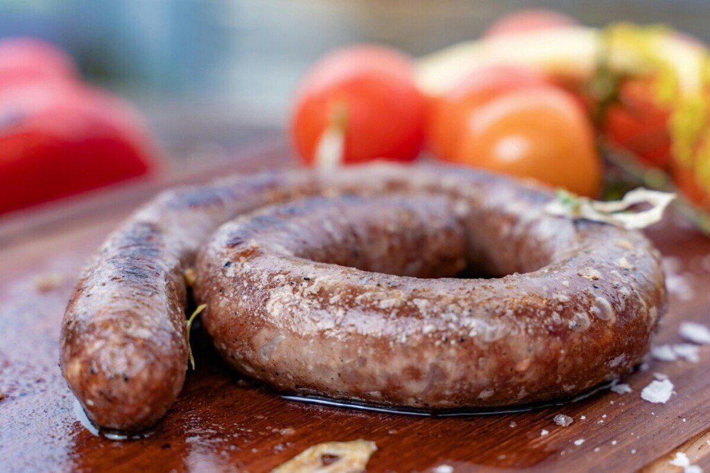 Close-up of grilled sausage on a wooden board with fresh tomatoes, Dubai setting.