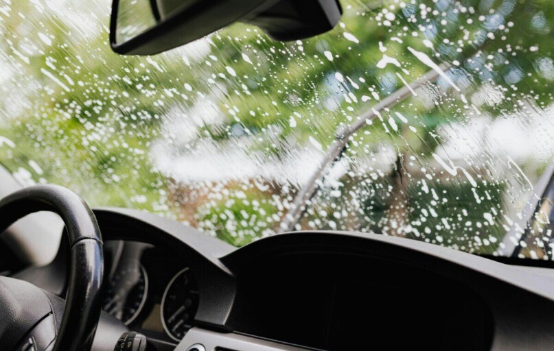 Interior view of a car with soapy windshield during cleaning. Clear dashboard visible.