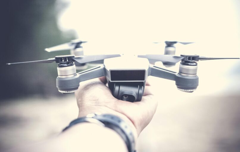 A close-up shot of a person holding a modern drone outdoors, showcasing its design and technology.