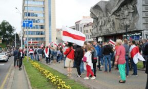 Crowd gathers for a protest in central Minsk, Belarus, holding flags and demonstrating peacefully.