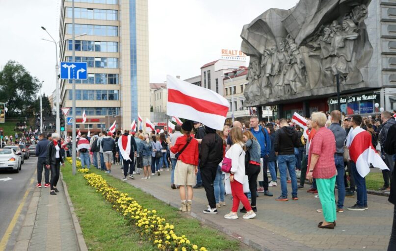 Crowd gathers for a protest in central Minsk, Belarus, holding flags and demonstrating peacefully.