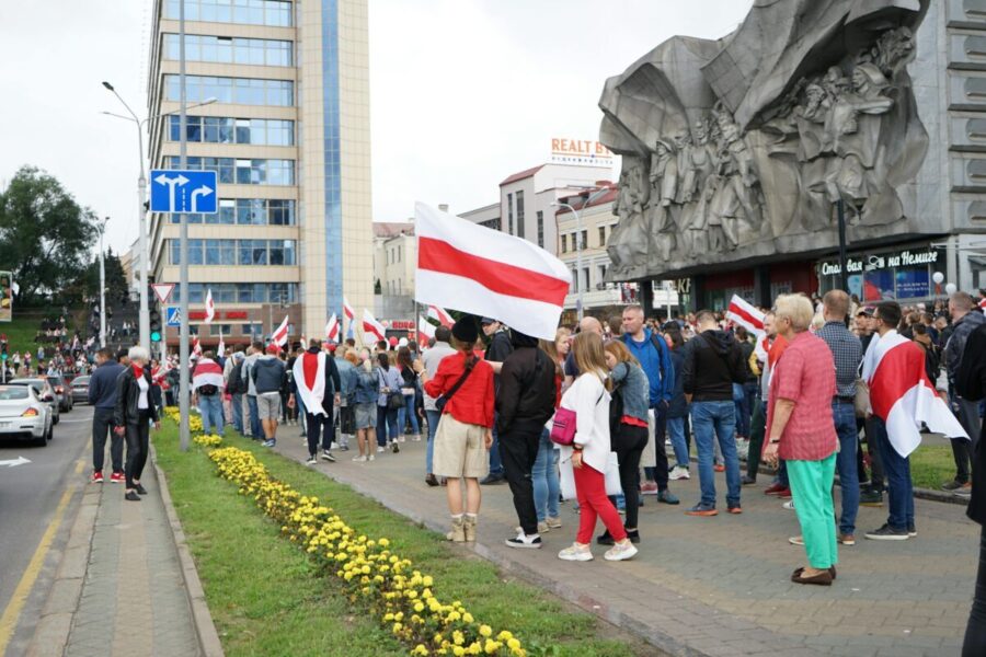 Crowd gathers for a protest in central Minsk, Belarus, holding flags and demonstrating peacefully.