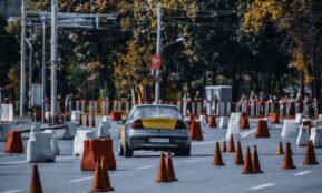 Participant in car race maneuvering between red and white traffic cones or barriers in front of audience