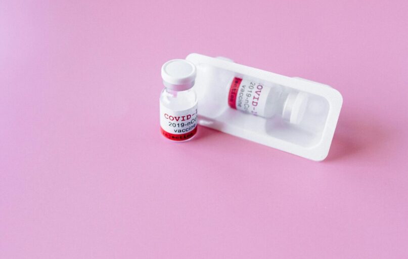 Close-up of COVID-19 vaccine vials on a pink surface, symbolizing healthcare and immunization.