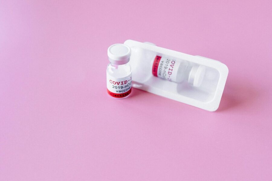Close-up of COVID-19 vaccine vials on a pink surface, symbolizing healthcare and immunization.