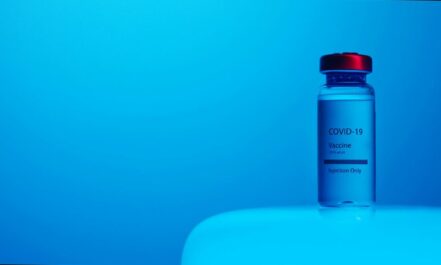 A COVID-19 vaccine vial with clear labeling on a serene blue background, symbolizing hope and health.