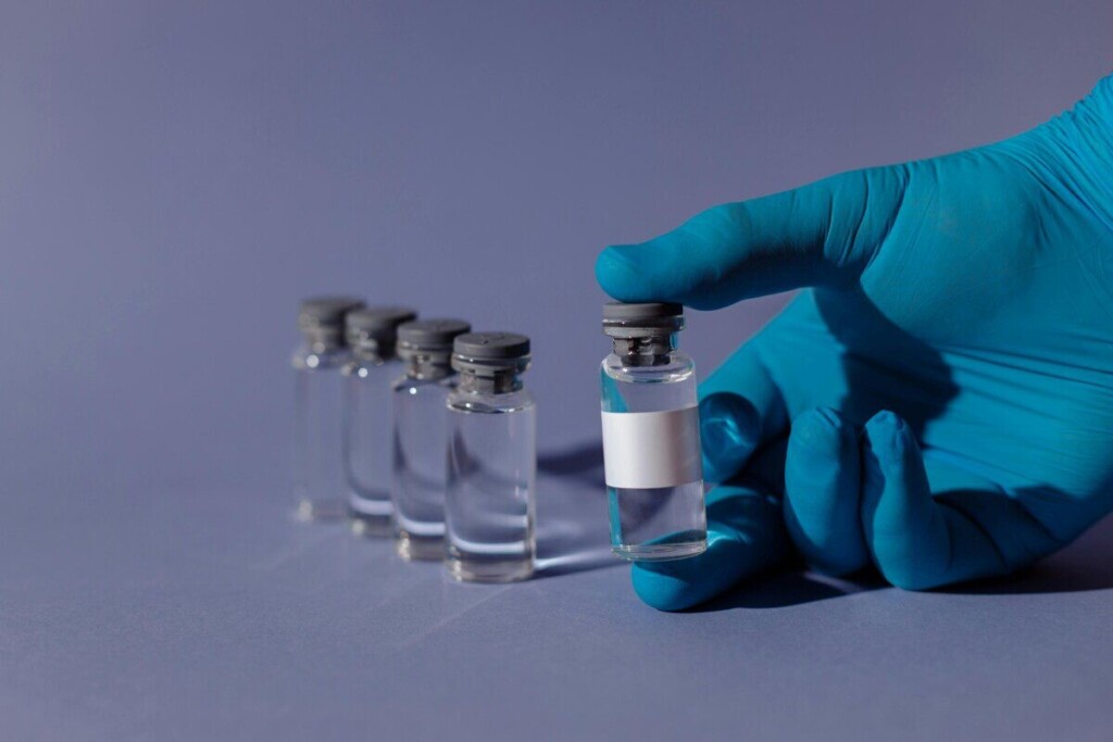Blue-gloved hand holding a transparent vial with liquid, representing healthcare and vaccination.