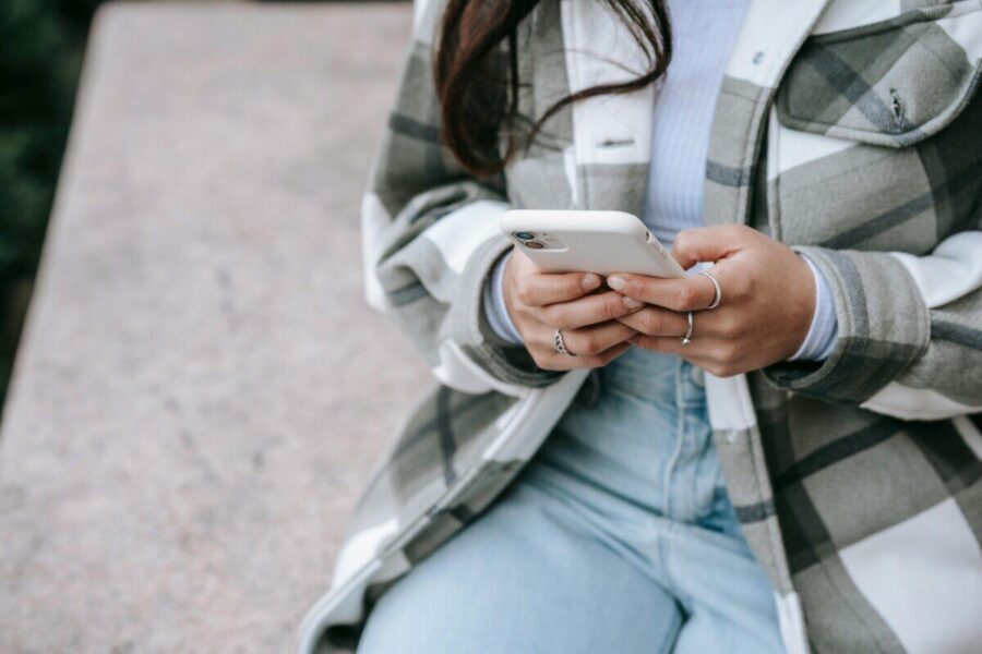 A woman using her smartphone while sitting outdoors, showcasing modern lifestyle and connectivity.