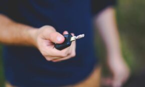 A hand holding a car key outdoors, emphasizing security and control.