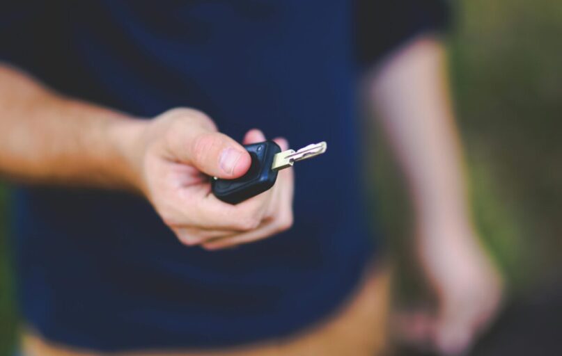 A hand holding a car key outdoors, emphasizing security and control.
