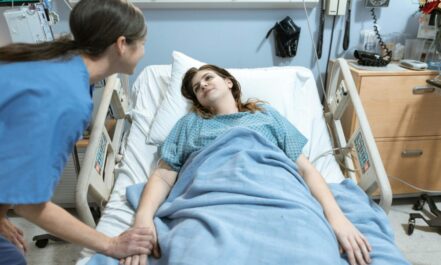 A nurse compassionately holds a patient's hand in a hospital room setting, promoting care and support.