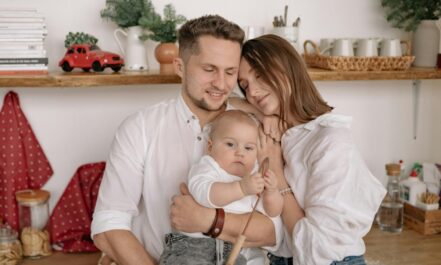 A joyful family of three embracing in a cozy kitchen. Warm and loving atmosphere.
