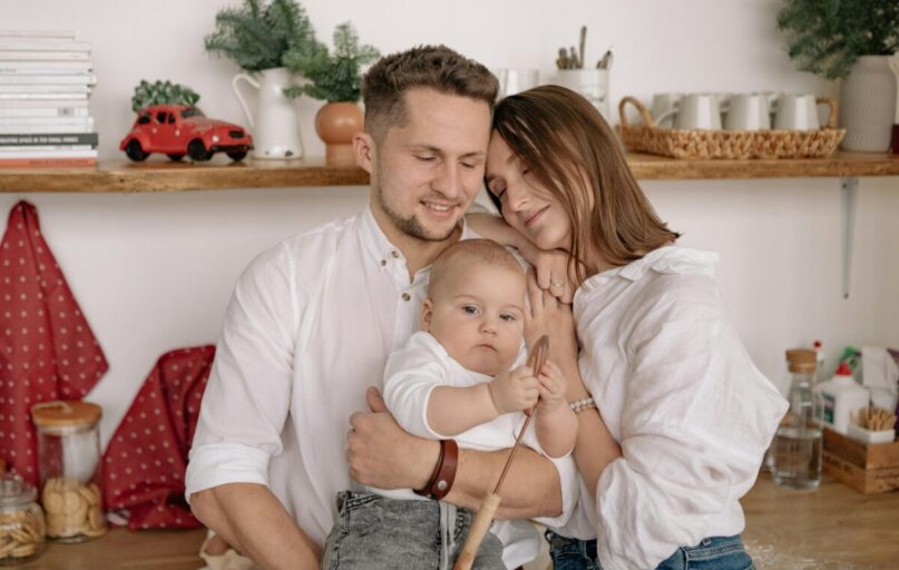 A joyful family of three embracing in a cozy kitchen. Warm and loving atmosphere.