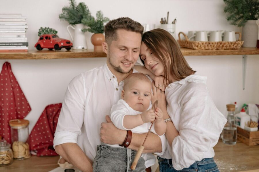 A joyful family of three embracing in a cozy kitchen. Warm and loving atmosphere.