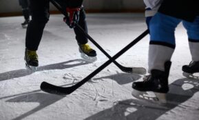 Close-up of hockey players battling for puck during an intense face-off on a lighted ice rink.