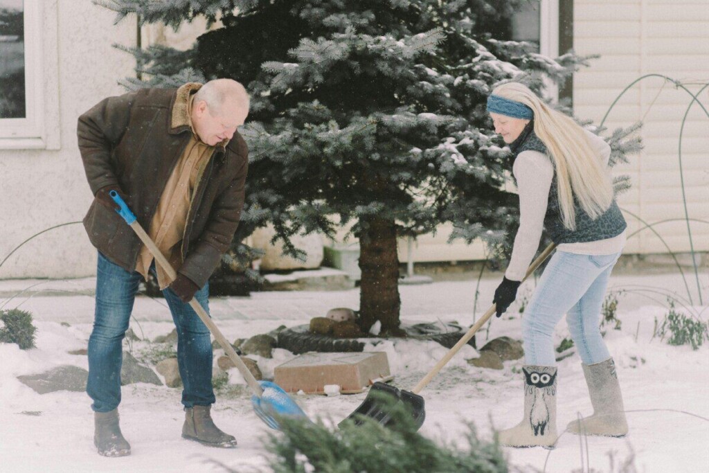 Elderly couple shoveling snow in winter, showcasing teamwork and outdoor activity.