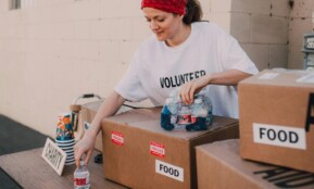 Woman volunteer sorting food and water for charity distribution at aid center.