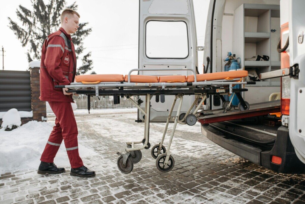 A paramedic loads a stretcher into an ambulance on a snowy day, showcasing emergency response readiness.