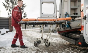 A paramedic loads a stretcher into an ambulance on a snowy day, showcasing emergency response readiness.