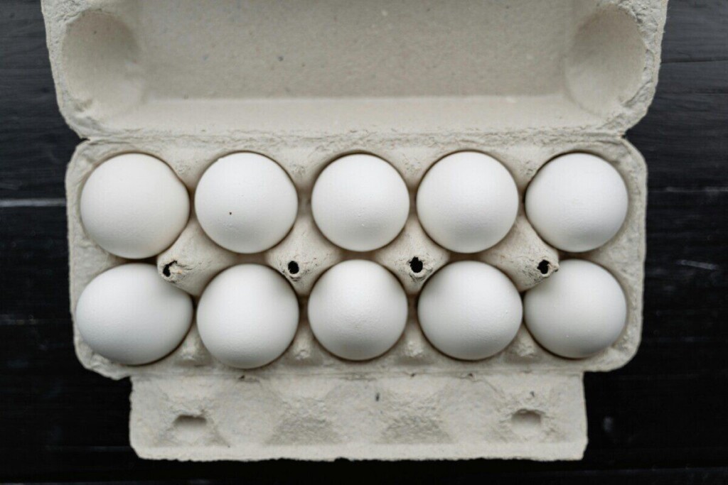A high-angle close-up of white eggs in a carton, ideal for food and culinary themes.