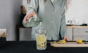 Woman pours water for lemon ginger infusion, promoting health and hydration.