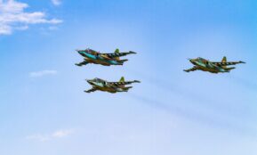 Sukhoi Su-25 aircrafts flying in perfect formation against a clear blue sky.