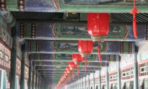 Close-up of traditional red lanterns hanging in Beijing's Summer Palace with intricate ceiling artwork.
