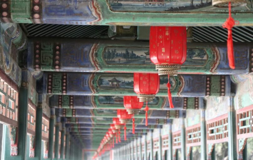 Close-up of traditional red lanterns hanging in Beijing's Summer Palace with intricate ceiling artwork.